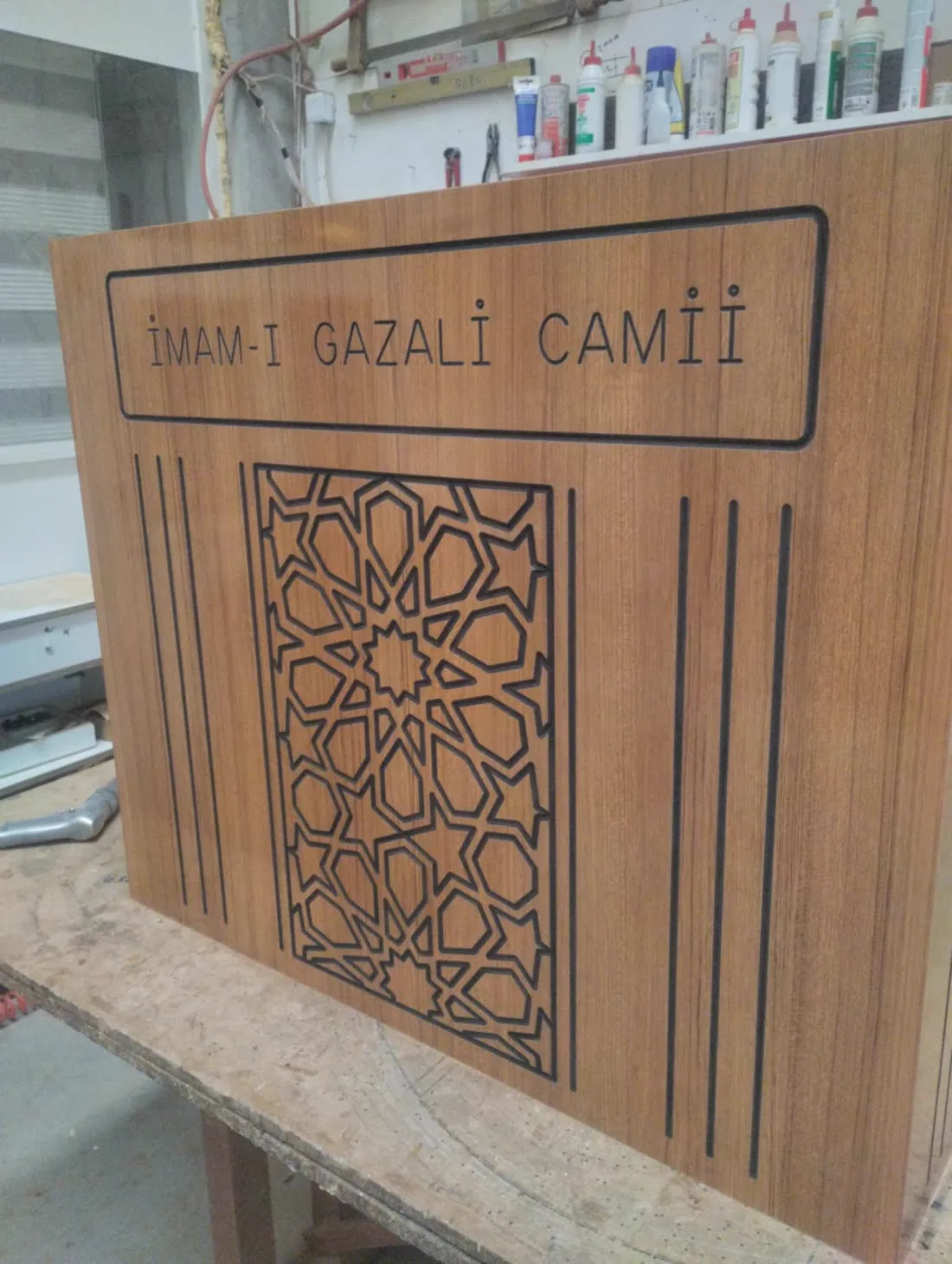 Cami ismi ve geometrik rozet oyulmuş ahşap panel